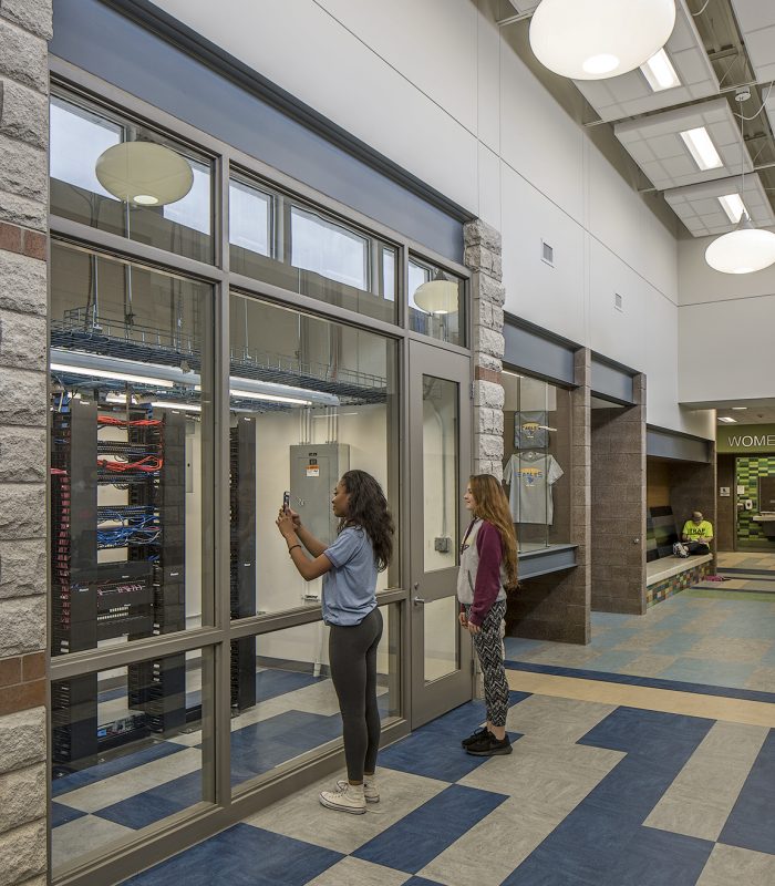 Students look through windows into the Liberty Middle School telecommunications room