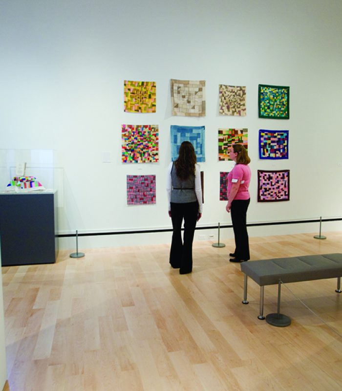 Students Lindsey Carroll (black vest) and Christine Humphrey (pink shirt) study quilts in the quilt galleries on the second floor of the International Quilt Study Center, 081014, Photo by Erik Stenbakken Photography.