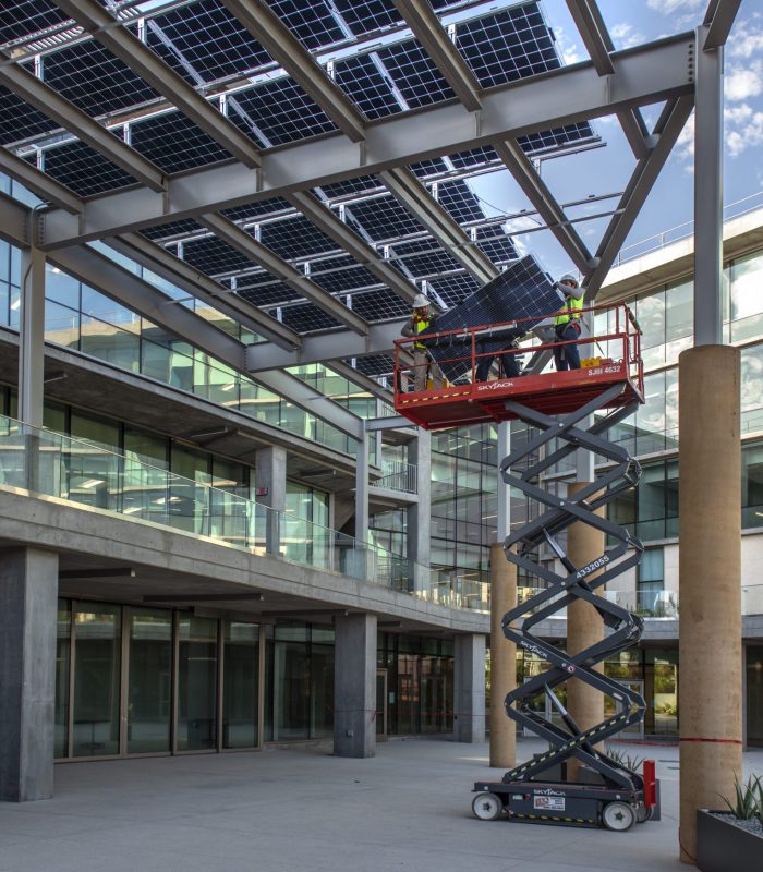 Exterior day shot of University of California, Irvine Susan and Henry Samueli College of Health Sciences building as they as putting up the solar panels on the roof